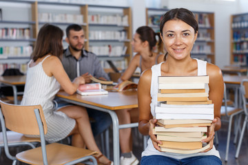 Happy girl with books sitting in classroom
