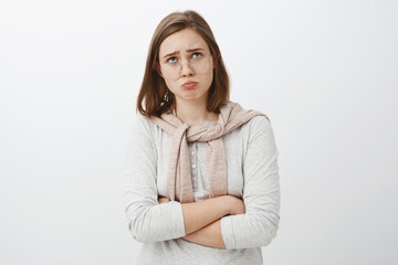 Sad gloomy offended silly girl in glasses and cute outfit folding lips, pouting frowning and...