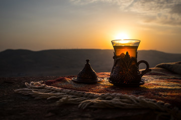 Arabian tea in glass on a eastern carpet. Eastern tea concept. Armudu traditional cup. Sunset background. Selective focus