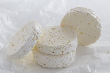 Feta cheese rounds close up on white parchment paper background