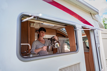 Woman cooking in camper, motorhome interior