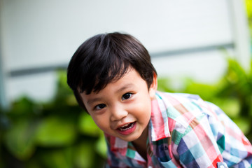 outdoor portrait of a cute little asian boy smiling in the park