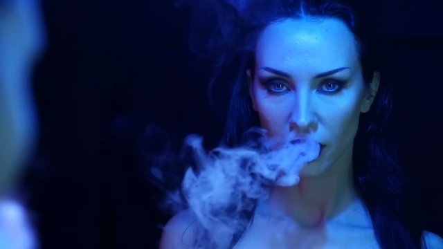 Night Party, Nightlife. Beautiful Sexy Woman Relax and smoking in the chill-out in a Nightclub