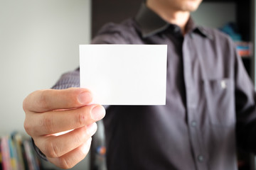 Man holding a business card background white wall. Business concept.