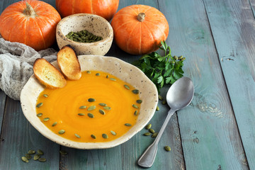 Pumpkin cream soup on a green wooden rustic table. Selective focus. Copy space.