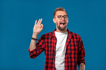 Emotional and people concept: young bearded man in checkered shirt. Hipster style. The guy shows his hand - It's okay or OK.