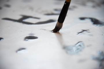 Close up on hand holding brush while writing calligraphy chinese or japanese language.