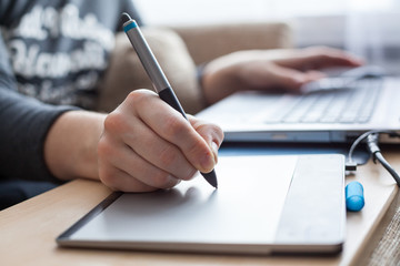 Close-up view at pen of drawing board painting on surface, woman illustrator