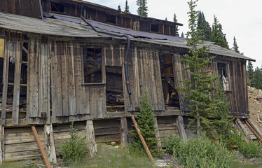 Fototapeta na wymiar Remains of old mine and vintage mining log cabin in the mountains in the western USA reflective of the pioneers from another generation