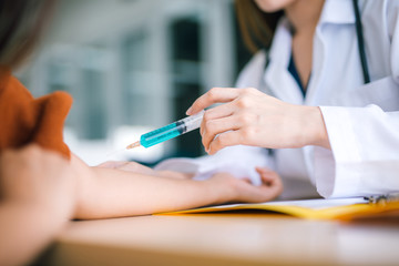 Fototapeta premium Female doctor Injection to the patient. hand press syringe to inject shot Vaccination and medical injection image.Healthcare, Medical vaccine concept.