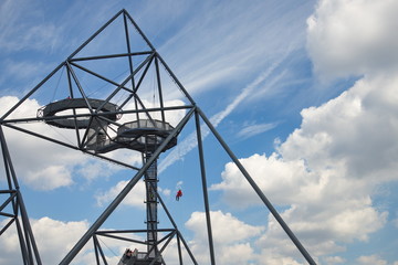 People rappel from top of the tetrahedron, steel tube structural sculpture which foam as pyramid or tetrahedron is located on the hill top of the mine dump Halde Beckstraße in Bottrop, Germany.