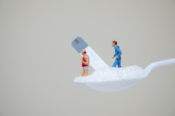 Man and fat oldman miniature figures running on spoon full with sugar and test strip for check blood sugar level. Sport, Fitness, Medicine, diabetes, glycemia, health care and people concept.