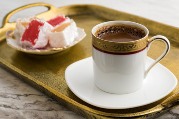 Vintage cup of turkish coffee and turkish delights served in bronze tray on marble
