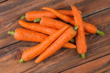 Pile of clean washed carrots. Top view. Wooden desk surface background.