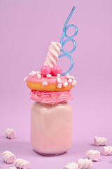 Pink strawberry freakshake with marshmallow and sweets.