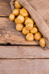 Young potatoes in a sack close up. Wooden desk background.