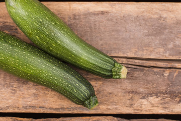 Two zucchini or courgettes on wood. Top view. Old vintage rustic wooden table.