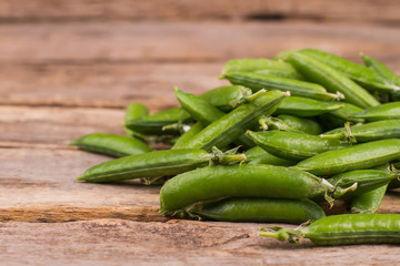 Pile of green fresh peas on the table. Close up. Old vintage rustic wood.