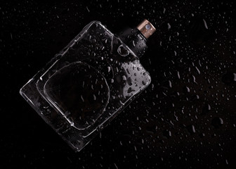 Bottle of perfume with drops of freshness on a black background.