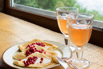 Herbal tea and  pancakes  with honey and berries on wooden table near the window
