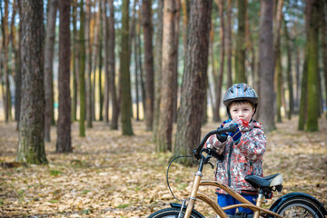 Young boy with bicycle with drinking clear water