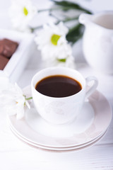 White cup of black coffee and chrysanthemums flowers on a white background