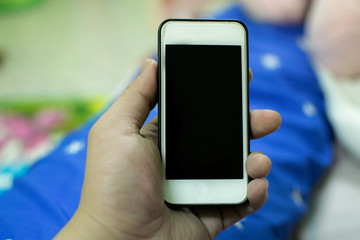 A white mobile phone in hand. And the background blurred.