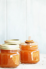 A row of mason jars full of homemade Cantaloupe Jam against a rustic background. Could also be peach jam.
