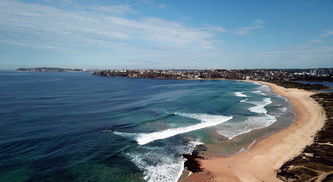 Bird view of Dee Why beach (Sydney, Australia) on a sunny but cold day in winter time. Manly and Sydney CBD in the background.