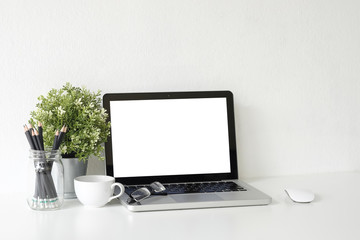 Fototapeta premium Workspace Mock up laptop computer on white table with mug of coffee, plat in pot and notebook paper copy space office table.