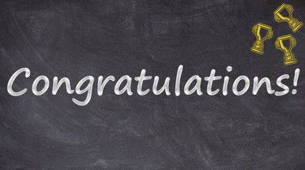 Obraz premium Congratulations text on blackboard with trophies
