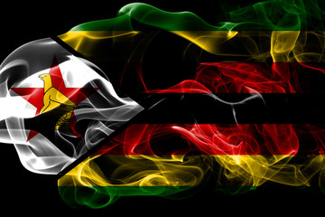 National flag of Zimbabwe made from colored smoke isolated on black background. Abstract silky wave background.