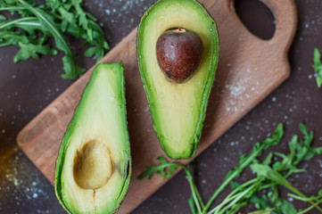 Cut avocado, arugula and olive oil on a chopping board