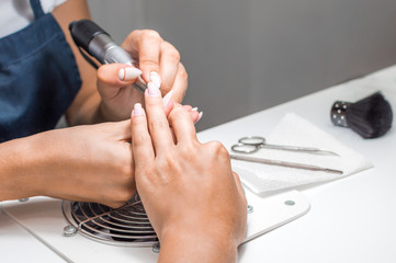 Manicurist does a manicure to a young woman. Close-up of hands