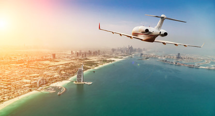 Avion à réaction privé volant au-dessus de la ville de Dubaï dans une belle lumière du coucher du soleil.