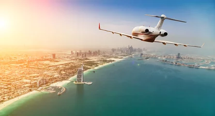 Foto auf Acrylglas Privates Düsenflugzeug, das über Dubai-Stadt im schönen Sonnenunterganglicht fliegt. © Jag_cz
