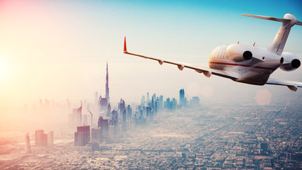 Private jet plane flying above Dubai city in beautiful sunset light. - obrazy, fototapety, plakaty