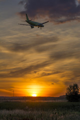 The plane flies against the sky during sunset.

