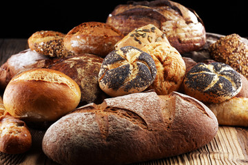 Different kinds of bread and bread rolls on board from above. Kitchen or bakery