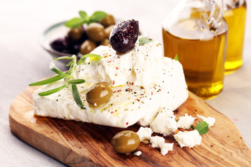 Greek cheese feta with herbs and olives on rustic table.