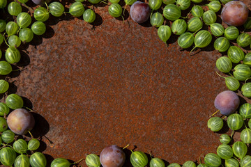 Rusty metal surface background with some fresh gooseberry and plums
