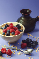 Healthy breakfast. White plate with oatmeal strewn and different berries on a blue background.