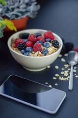 Healthy breakfast. White plate with oatmeal strewn and different berries on a blue background. Summer harvest.
