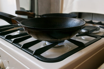 black cast-iron pan is on a gas stove, close up.
