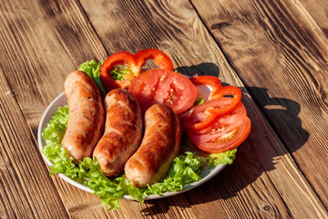 Grilled sausages with fresh vegetables on wooden table