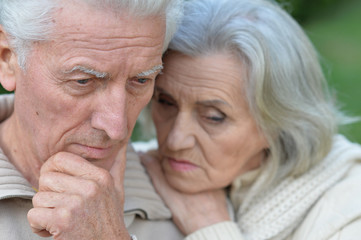 Portrait of a sad senior couple in park