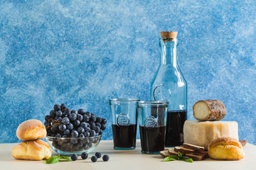 Red wine in the bottle and recycled glassware on the table. fresh grapes, bread and cheese. Mediterranean food