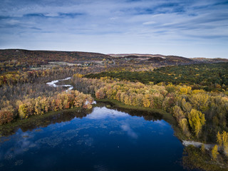 Fototapeta premium Aerial view over forest and river during vibrant autumn colors vibrant autumn colors