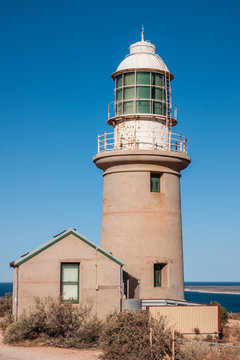 Exmouth, Western Australia - November 27, 2009: Vlaming Head Lighthouse overlooking Indian Ocean against deep blue sky. Beige concrete construction with white metal top and green glass.