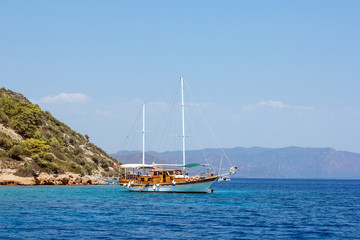 Closer view on beautiful wooden yacht with white hull sailing in the turquoise blue sea among islands